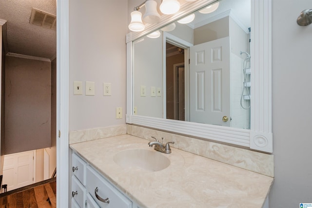 bathroom with wood-type flooring, ornamental molding, a textured ceiling, and vanity