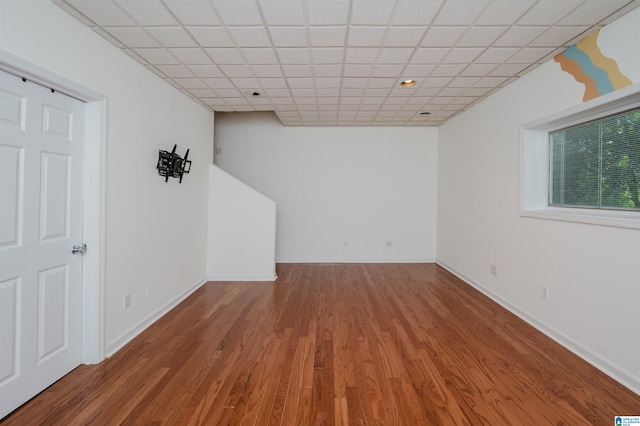 spare room featuring wood-type flooring and a drop ceiling