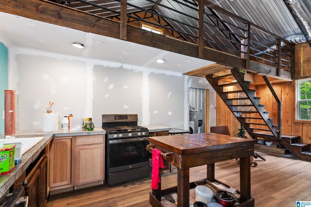 kitchen featuring gas stove, wooden walls, and light hardwood / wood-style floors