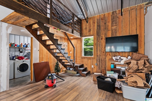 workout area with vaulted ceiling, wood-type flooring, washing machine and clothes dryer, and wood walls