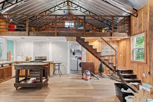 interior space featuring high vaulted ceiling, light hardwood / wood-style flooring, wood walls, and independent washer and dryer