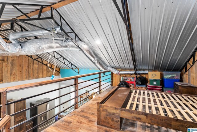 interior space featuring vaulted ceiling, wood walls, and hardwood / wood-style flooring