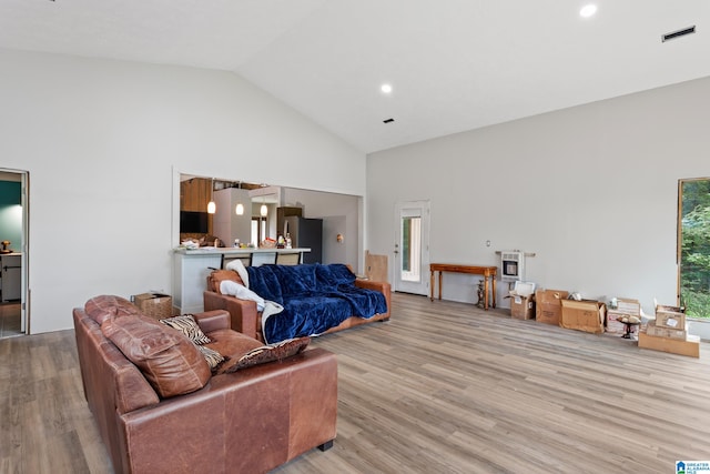 living room featuring high vaulted ceiling, light wood-type flooring, and heating unit