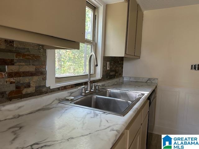 kitchen with tasteful backsplash, light stone countertops, and sink