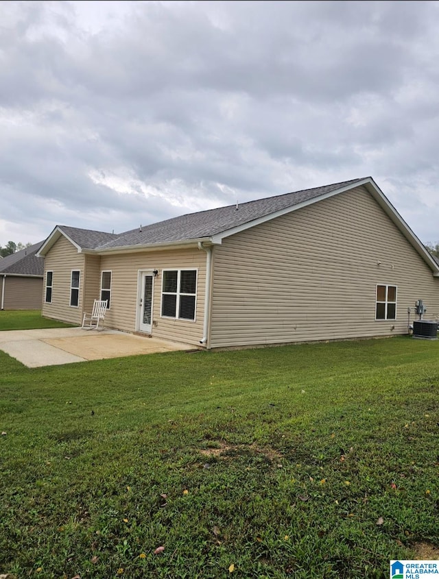 rear view of house with central AC, a patio area, and a yard