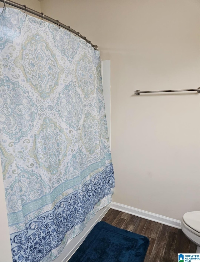 bathroom featuring walk in shower, hardwood / wood-style flooring, and toilet