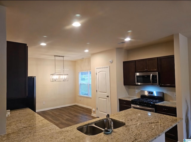 kitchen with light stone countertops, sink, pendant lighting, and stainless steel appliances