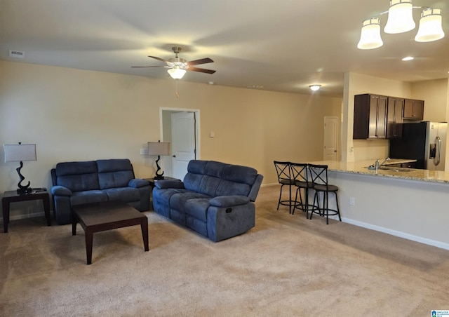 living room with ceiling fan with notable chandelier and light colored carpet