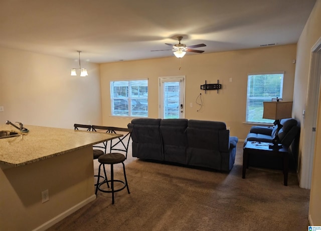 carpeted living room with ceiling fan and sink