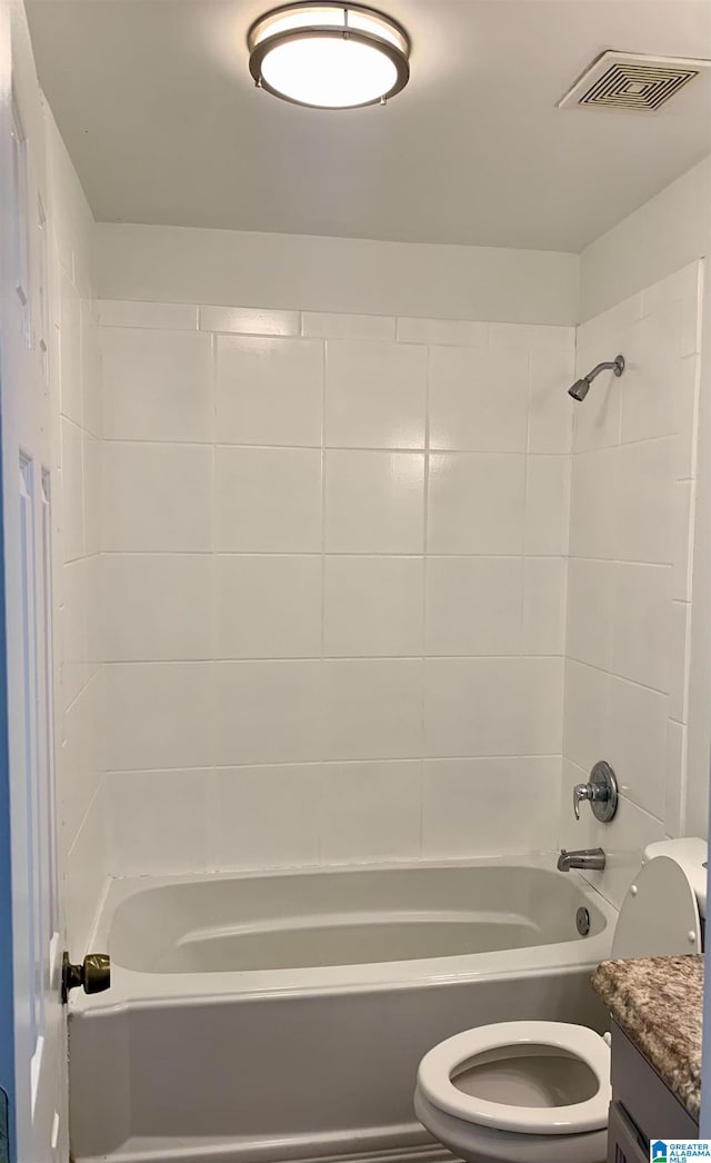 full bathroom featuring vanity, tiled shower / bath, and toilet