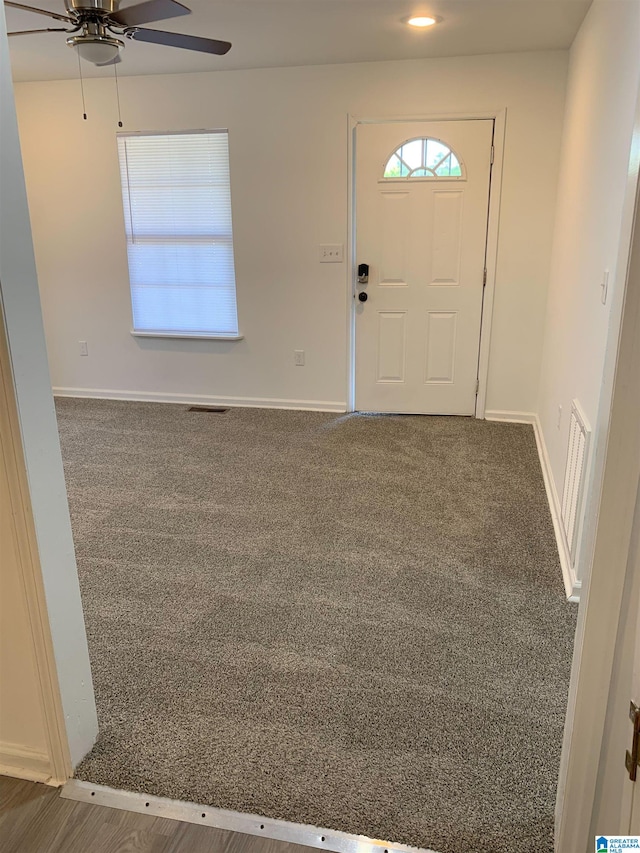 entrance foyer with dark colored carpet and ceiling fan