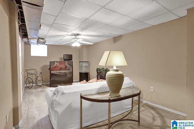 living room featuring light wood-type flooring, ceiling fan, and a drop ceiling