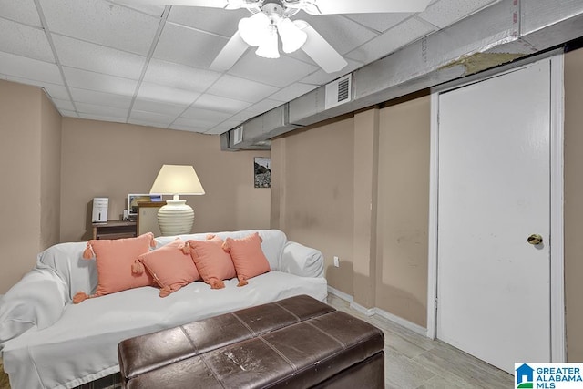 living room featuring ceiling fan, a drop ceiling, and light hardwood / wood-style flooring