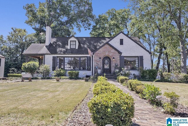 949 44th St, Birmingham, AL 35208 - tudor-style house with a front lawn, a chimney, and brick siding