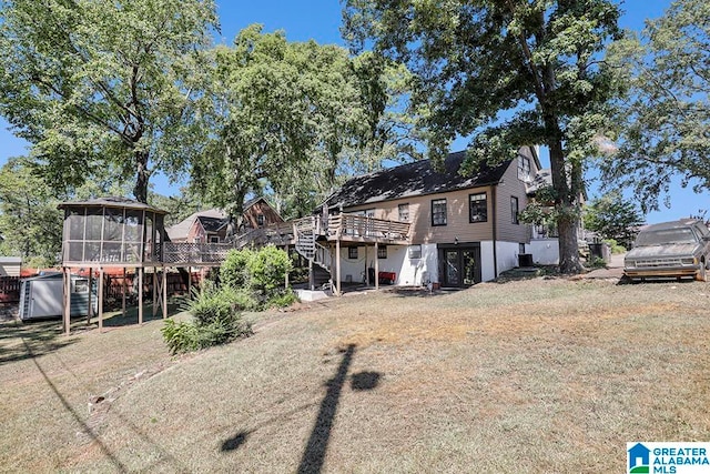 back of property with a yard, a sunroom, and a deck