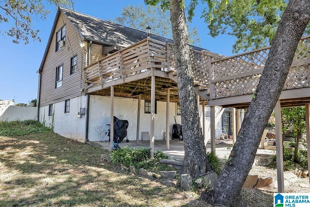 back of property with a wooden deck and a patio area