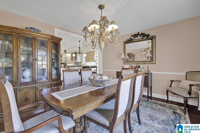 dining area with hardwood / wood-style flooring, a notable chandelier, and a textured ceiling