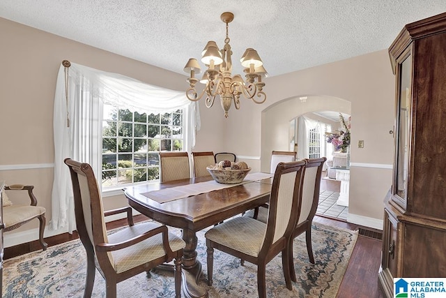 dining space with a textured ceiling, a notable chandelier, and dark hardwood / wood-style flooring