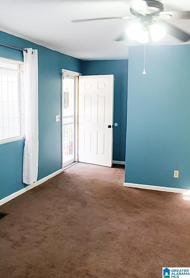 unfurnished room with dark carpet and ceiling fan