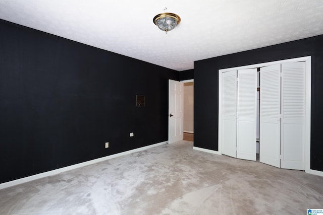 unfurnished bedroom with light carpet, a textured ceiling, and a closet