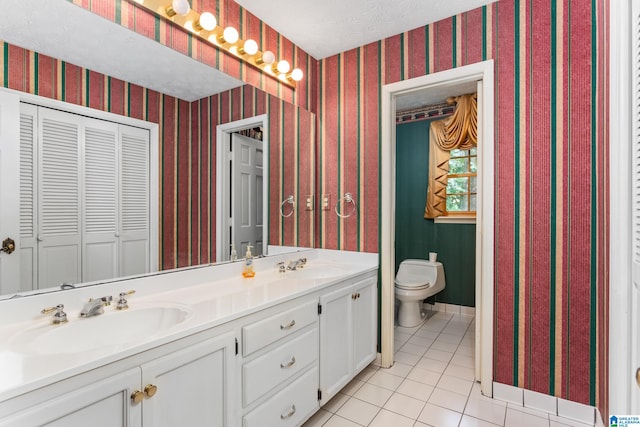 bathroom with a textured ceiling, vanity, toilet, and tile patterned floors