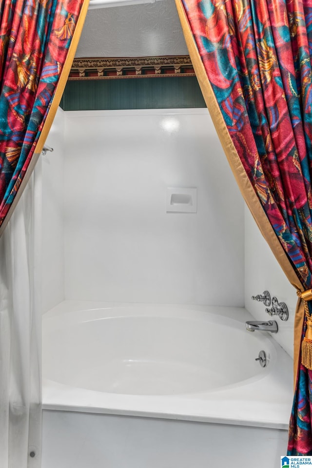 bathroom featuring a textured ceiling and a tub