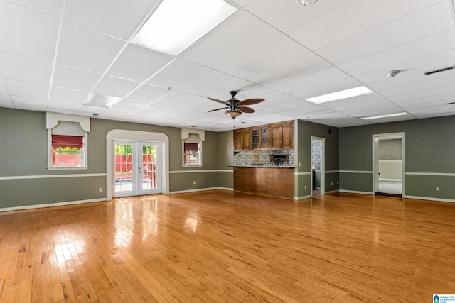 unfurnished living room featuring french doors, light hardwood / wood-style flooring, a paneled ceiling, and ceiling fan