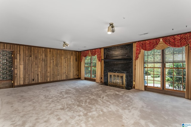 unfurnished living room featuring wooden walls, a large fireplace, and carpet flooring