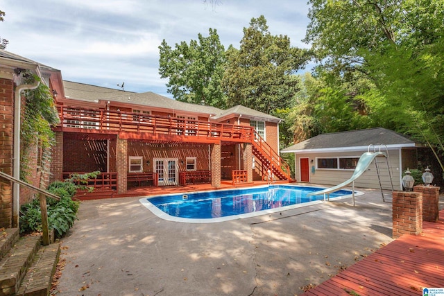 view of swimming pool featuring a water slide, a patio area, a deck, and french doors