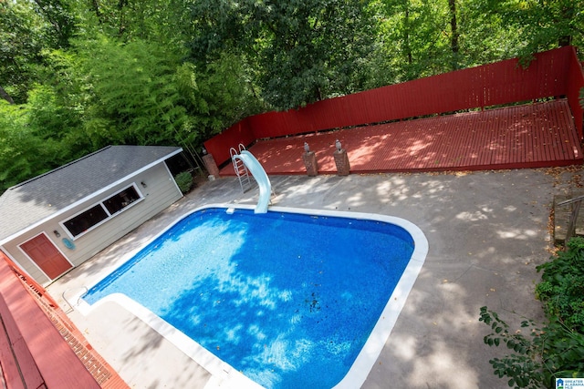 view of swimming pool featuring a water slide, an outbuilding, and a patio