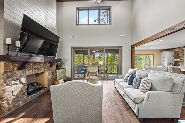 living room featuring dark wood-type flooring, a high ceiling, and a fireplace