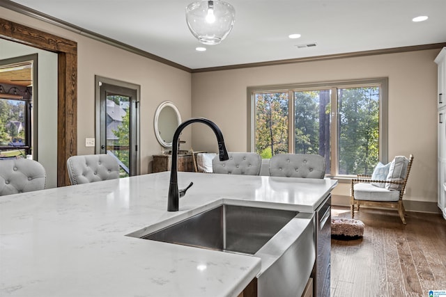 kitchen featuring ornamental molding, dark wood-type flooring, light stone counters, and sink