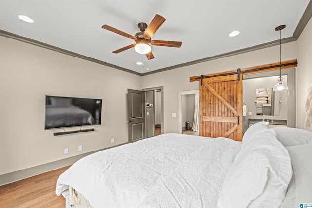 bedroom with crown molding, a barn door, wood-type flooring, and ceiling fan