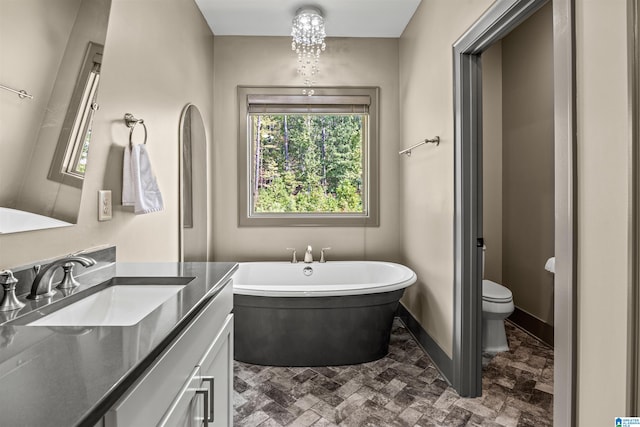 bathroom featuring vanity, toilet, a tub to relax in, and a notable chandelier