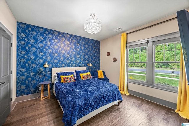 bedroom with dark wood-type flooring and a notable chandelier