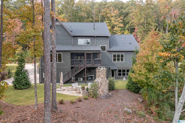 rear view of house featuring a patio, a lawn, and a sunroom