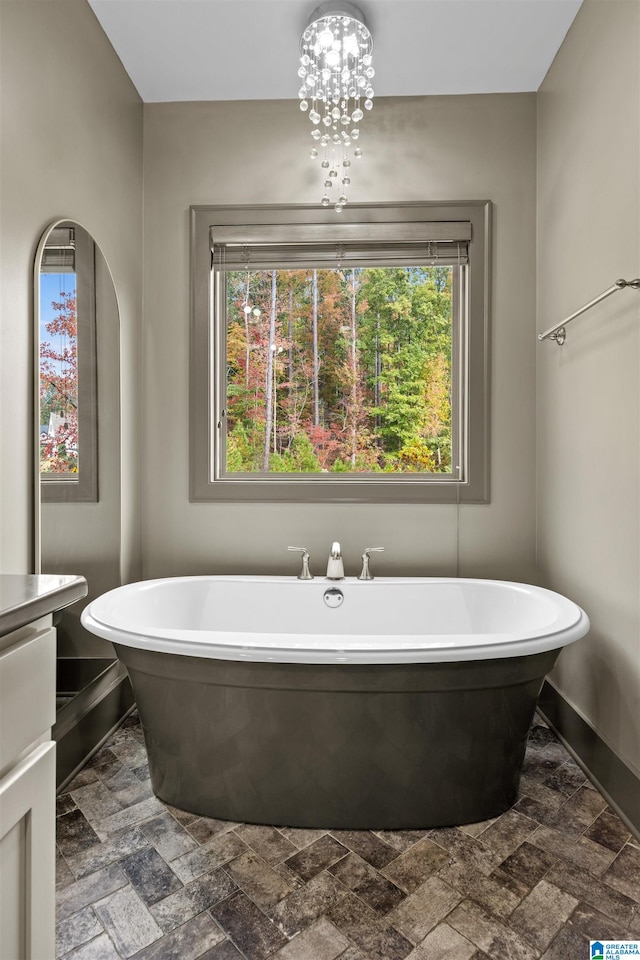 bathroom featuring vanity, a tub, and a notable chandelier