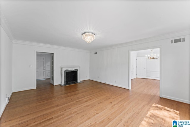 unfurnished living room with ornamental molding, a premium fireplace, hardwood / wood-style floors, and an inviting chandelier