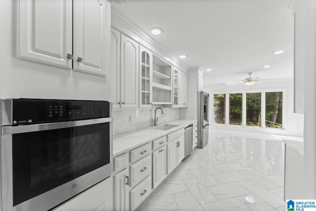 kitchen featuring white cabinetry, stainless steel appliances, sink, ceiling fan, and decorative backsplash