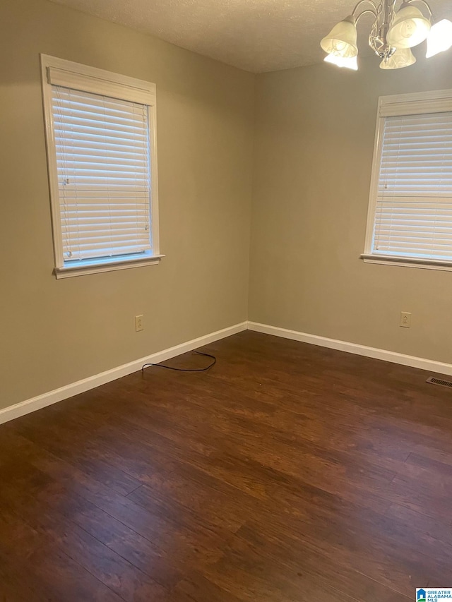 spare room featuring dark hardwood / wood-style flooring and a notable chandelier