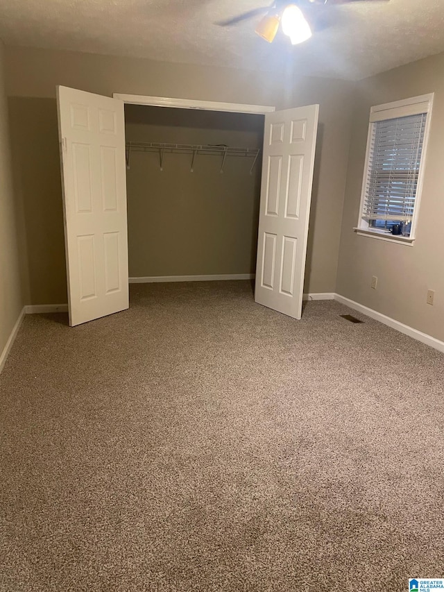 unfurnished bedroom featuring ceiling fan, a closet, and carpet floors