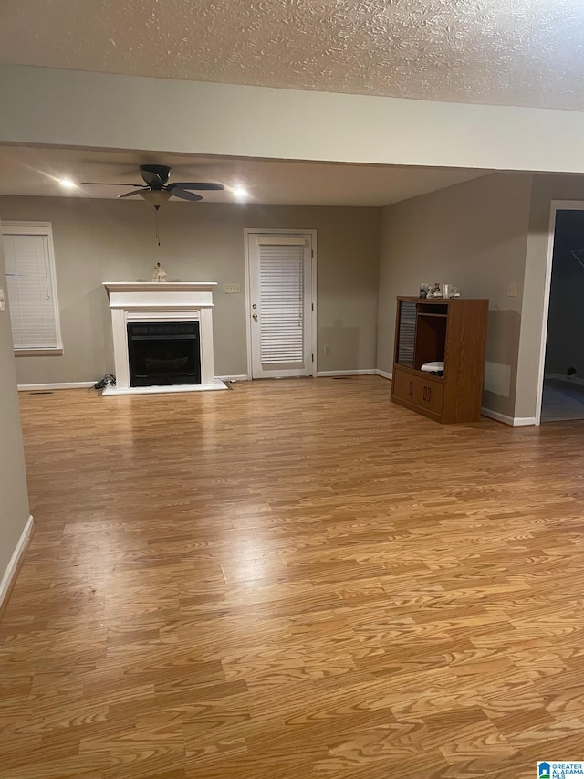 unfurnished living room with a textured ceiling, ceiling fan, and light hardwood / wood-style floors