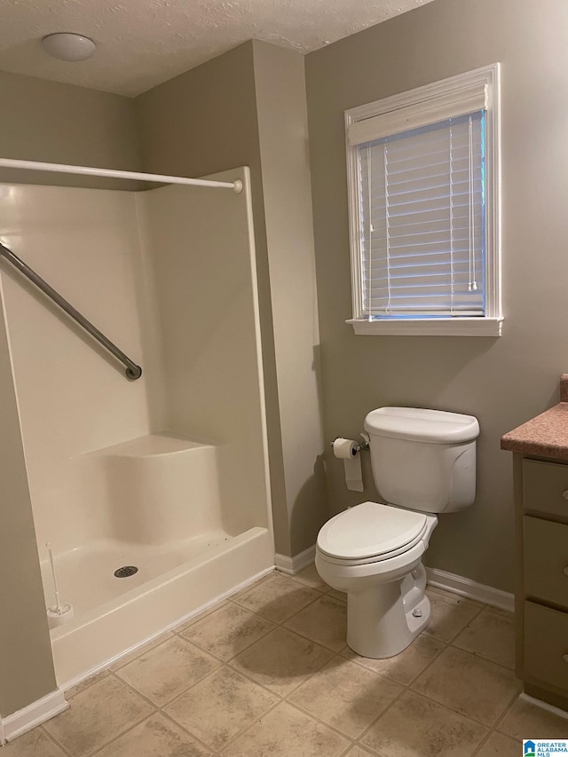 bathroom featuring toilet, walk in shower, tile patterned flooring, vanity, and a textured ceiling