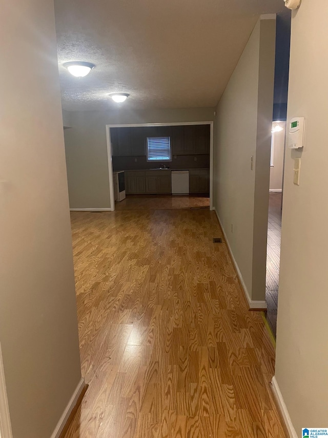 hall featuring light wood-type flooring and a textured ceiling