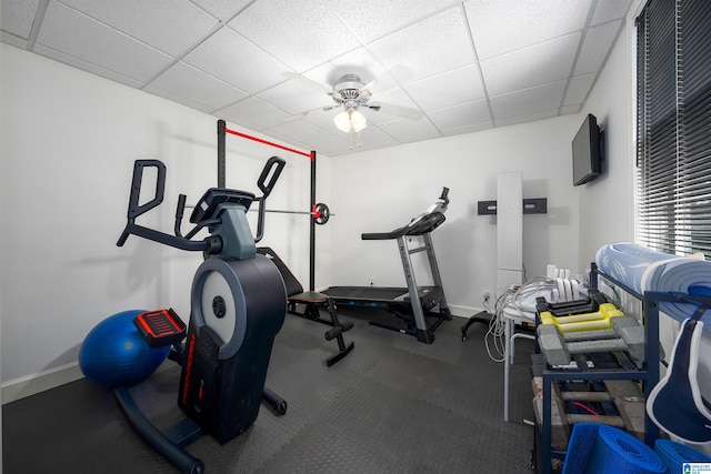 exercise area with ceiling fan, baseboards, and a drop ceiling