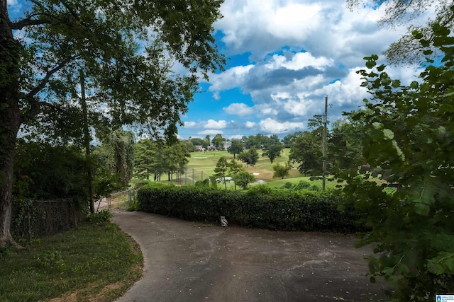 view of home's community featuring view of golf course and fence