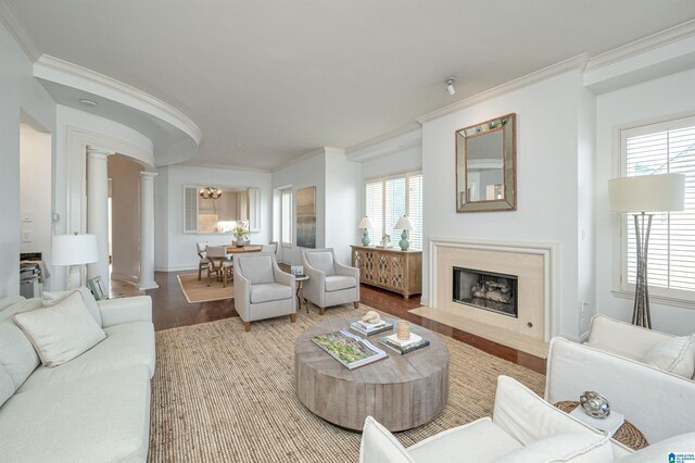 living room featuring ornamental molding, a high end fireplace, wood-type flooring, and ornate columns