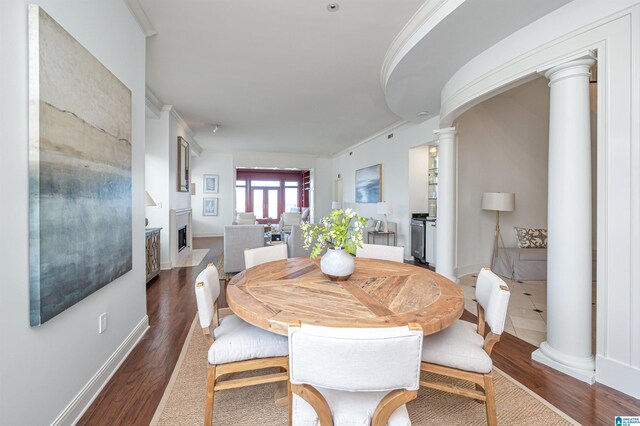 dining area featuring ornamental molding, decorative columns, and dark hardwood / wood-style floors