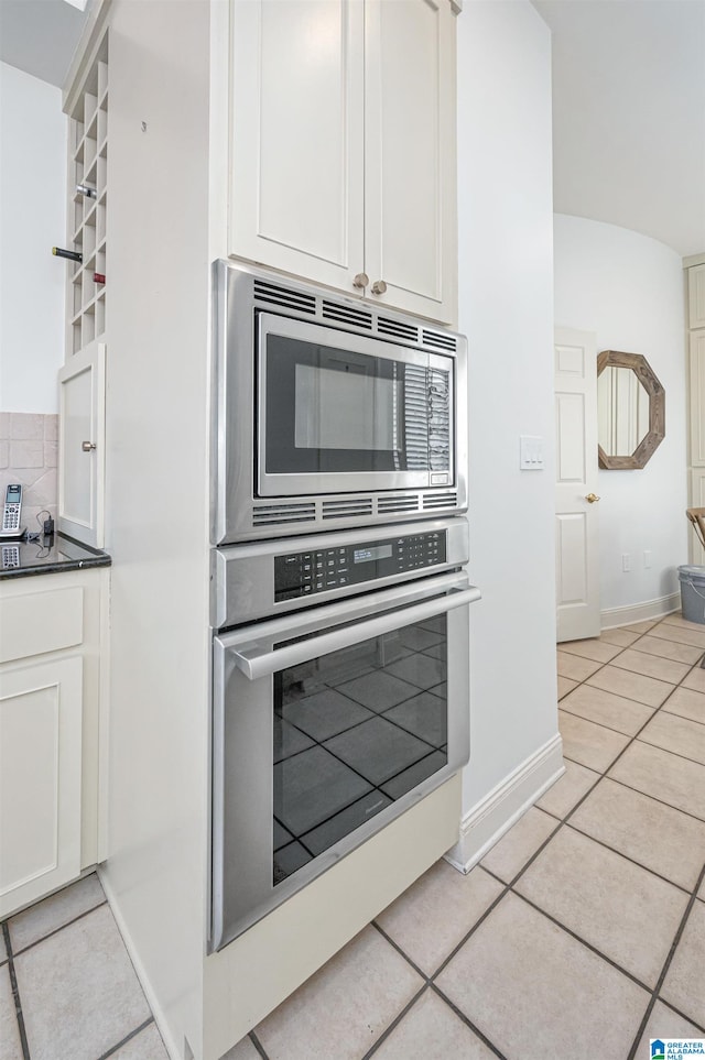 kitchen with light tile patterned floors, stainless steel appliances, and white cabinets