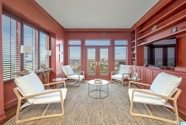 living area with a wealth of natural light, hardwood / wood-style flooring, ornamental molding, and french doors